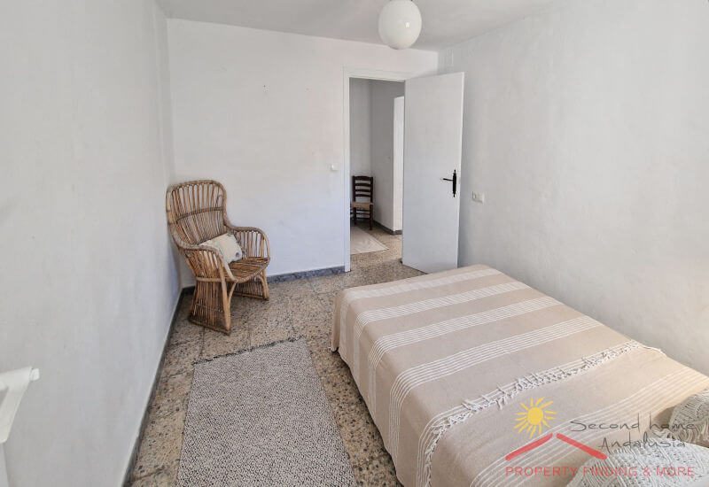 Eenvoudige slaapkamer met eenpersoonsbed en ruimte voor stoel