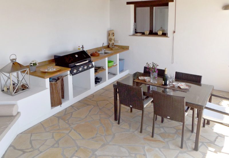 Foto van zomerkeuken met uitzicht op keuken en eettafel