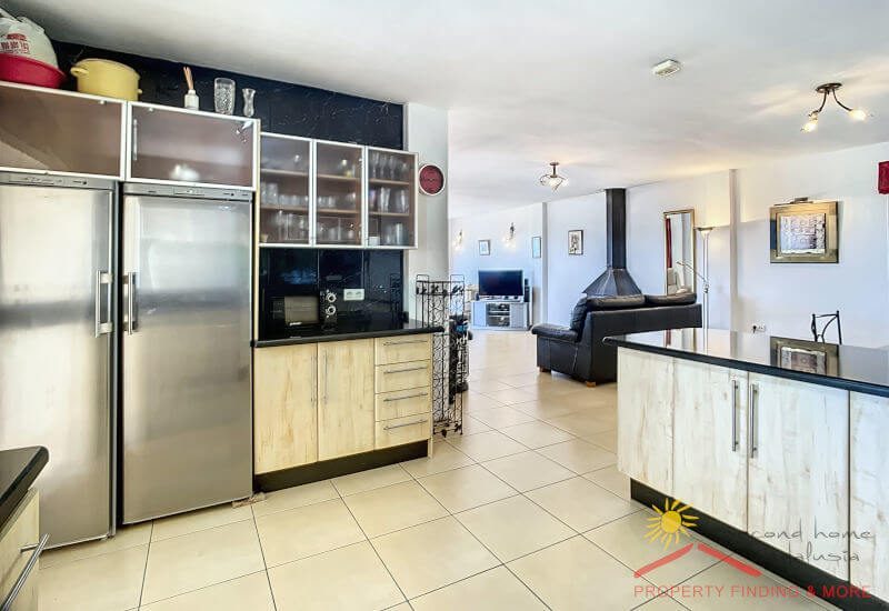The kitchen has a large refrigerator and is open to the living room.