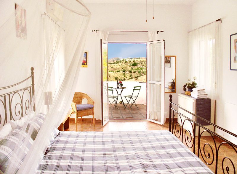 The master bedroom has two windows and a door towards the terrace with a beautiful view on the landscape.