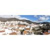 Gorgeous panoramic view of Sedella with mountains inwhite clouds and a blue sky.