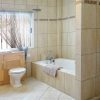 Large bathroom with bathtub, toilet and cupboard, as well as window