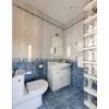 Badkamer in hoekkamer met witte en blauwe tegels en een douche.