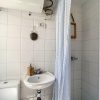 Small bathroom with shower, washbasin and toilet. Light through the window.